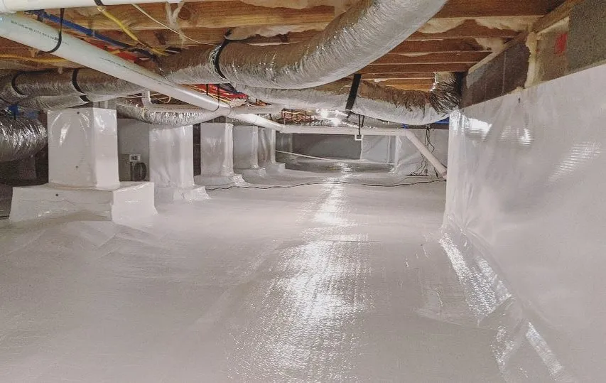 Clean encapsulated crawl space with a bright white vapor barrier floor liner and wrapped piers beneath the floor joists